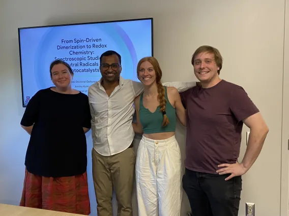 Picture of four people standing in front of a presentation