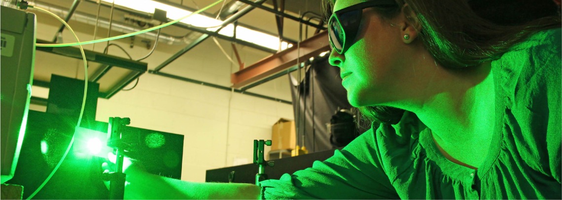 Woman looking at green laser beam on a card while wearing laser goggles