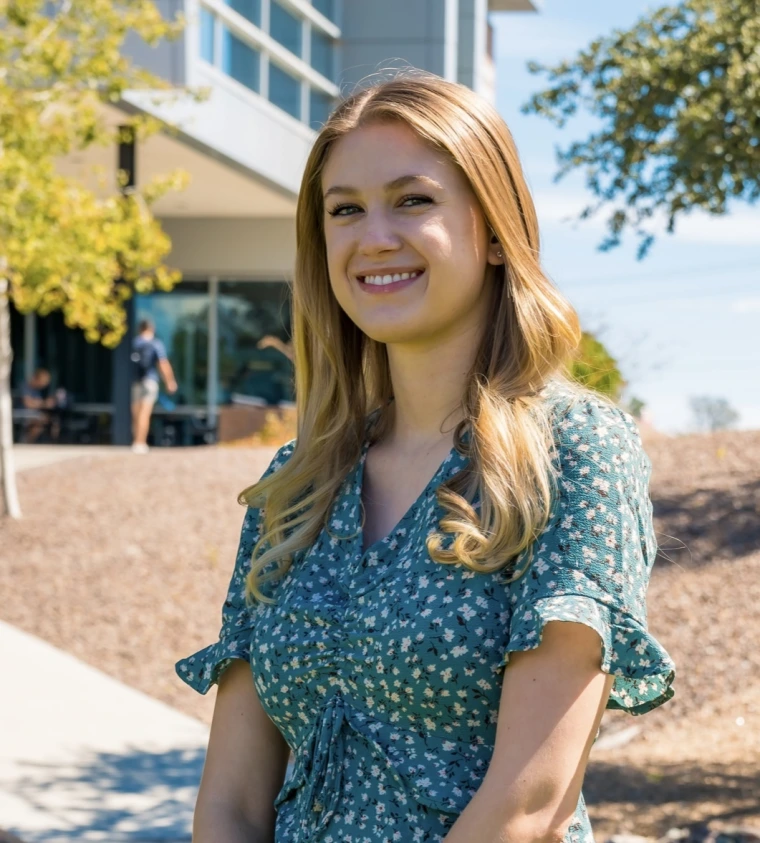 Photo of woman standing with a building in the background